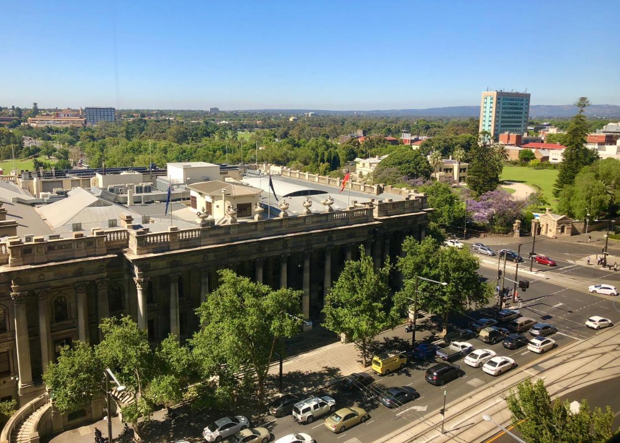 מלון Stamford Plaza אדלייד מראה חיצוני תמונה The photo depicts a cityscape view, showcasing a mix of architectural structures and greenery. In the foreground, there is a large, classical building with columns, suggesting it may be a historical or governmental structure. Surrounding the building